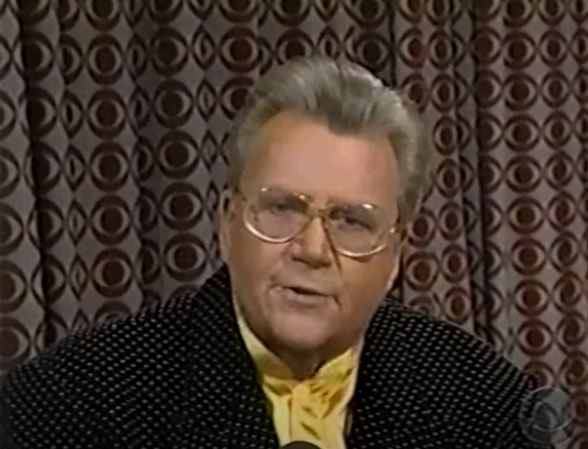 Rod is wearing a black jacket with white dots & a yellow silk collarless shirt