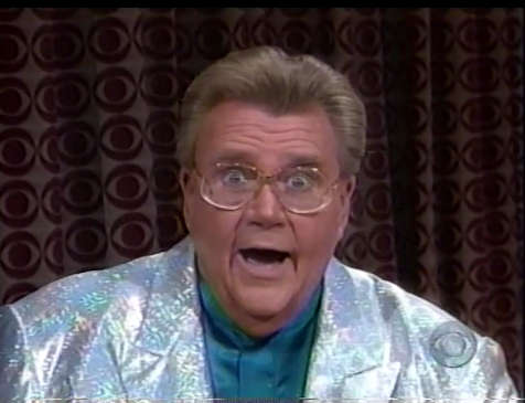 Rod is wearing a shiny holographic silver jacket & teal-green collarless silk shirt