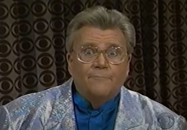 Rod is wearing a silver jacket & blue collarless silk shirt