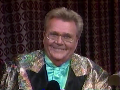 Rod is wearing a shiny iridescent jacket with black lapels & a powder-blue collarless silk shirt