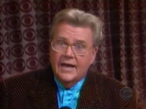 Rod is wearing a brown jacket with white dots & light-blue collarless silk shirt