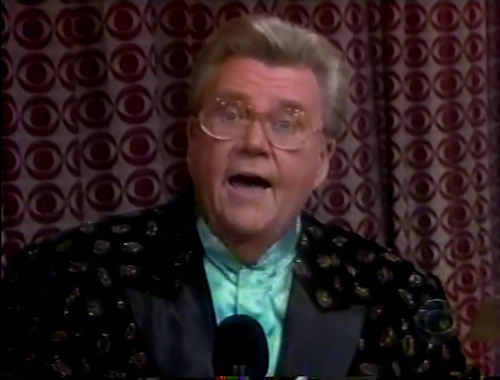 Rod is wearing a black jacket with shiny spots & seafoam-green collarless silk shirt