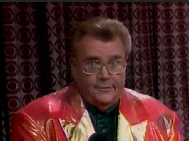 Rod is wearing a shiny salmon jacket with gold lapels & dark-green collarless silk shirt