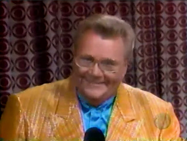 Rod is wearing a shiny yellow/yellow striped jacket & light-blue collarless silk shirt
