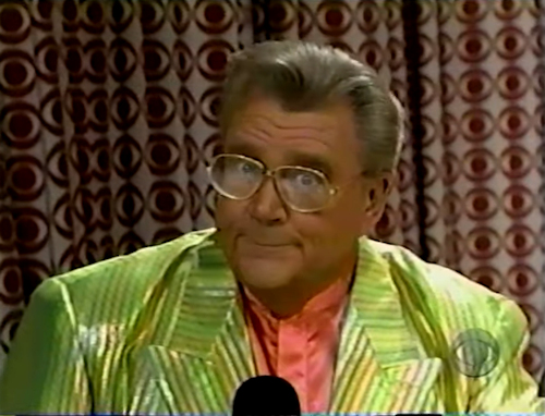 Rod is wearing a shiny lime-green/yellow-striped jacket & salmon collarless silk shirt