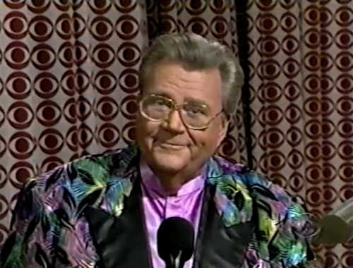 Rod is wearing a multi-colored feather-pattern jacket with black lapels & lavender collarless silk shirt