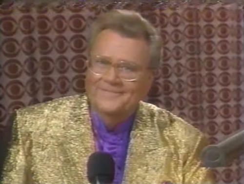 Rod is wearing a shiny gold jacket & purple collarless silk shirt