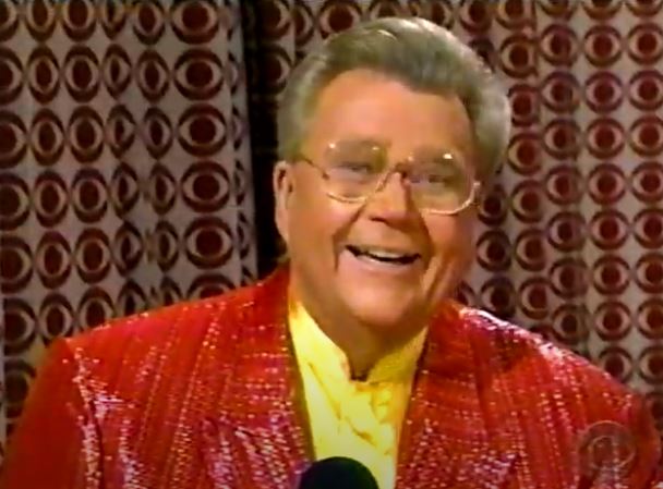 Rod is wearing a red sequined jacket & yellow collarless silk shirt