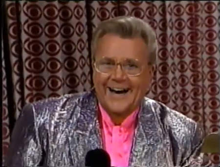 Rod is wearing a shiny silver jacket & pink collarless silk shirt