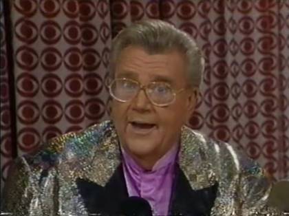 Rod is wearing a gold sequined jacket with black lapels & lavender collarless silk shirt