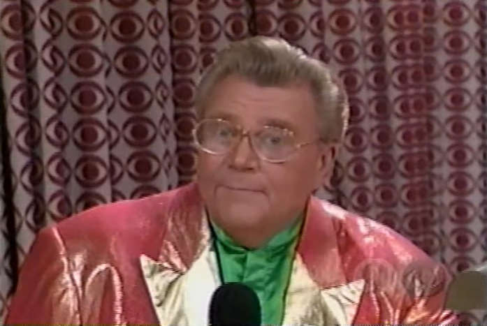 Rod is wearing a shiny peach jacket with gold lapels & a green collarless silk shirt