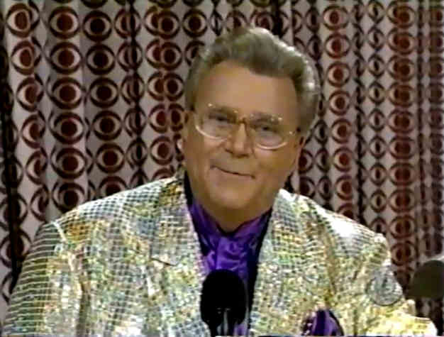 Rod is wearing a gold sequined jacket, purple collarless silk shirt & matching pocket square