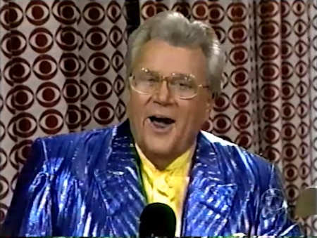 Rod is wearing a shiny blue/blue striped jacket & yellow collarless silk shirt