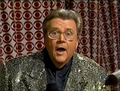 Rod is wearing a dark-gold sequined jacket & black collarless silk shirt
