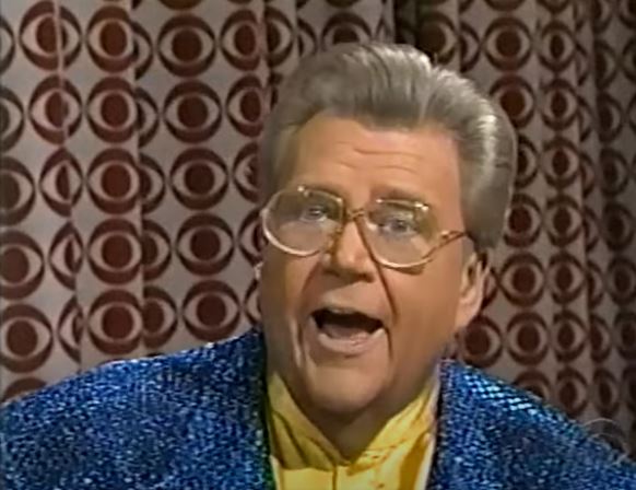 Rod is wearing a blue sequined jacket & yellow collarless silk shirt