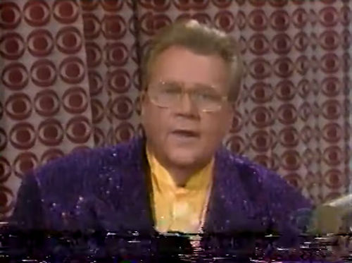 Rod is wearing a purple sequined jacket & yellow collarless silk shirt