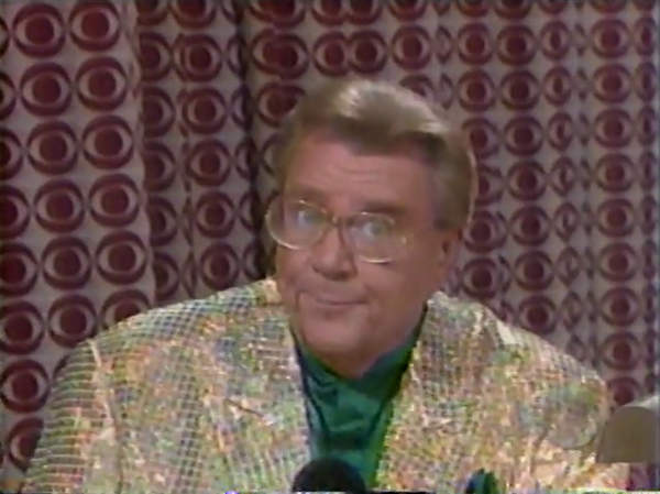 Rod is wearing a gold sequined jacket & dark-green collarless silk shirt with matching pocket square