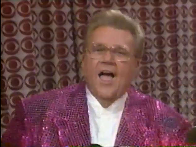 Rod is wearing a purple sequined jacket & white collarless silk shirt