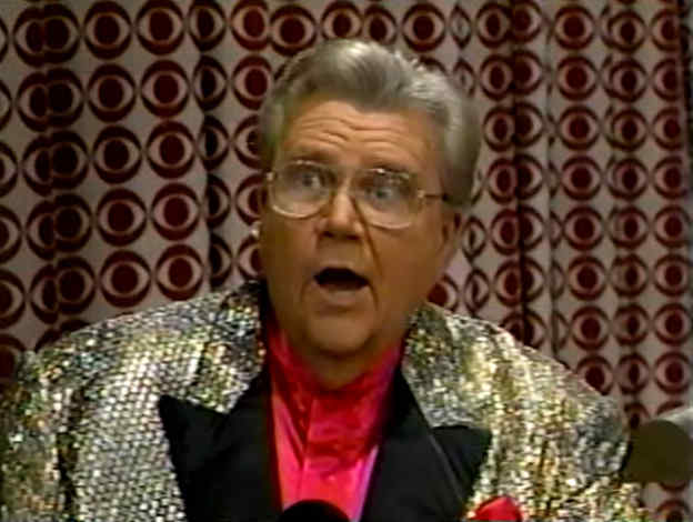 Rod is wearing a gold sequined jacket with black lapels & red collarless silk shirt with matching pocket square