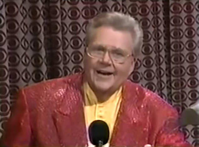 Rod is wearing a red sequined jacket & yellow collarless silk shirt