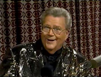 Rod is wearing a Rod is wearing a black jacket with silver sequins & a black collarless silk shirt