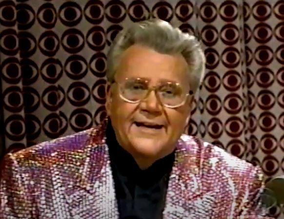 Rod is wearing an iridescent purple/pink/gold sequined jacket & black collarless silk shirt