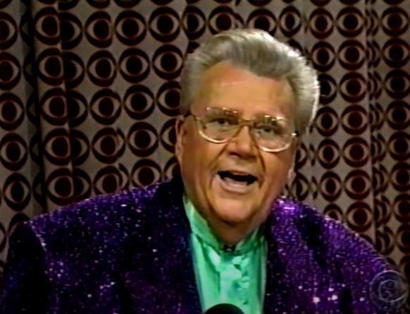 Rod is wearing a purple-sequined jacket & green silk collarless shirt