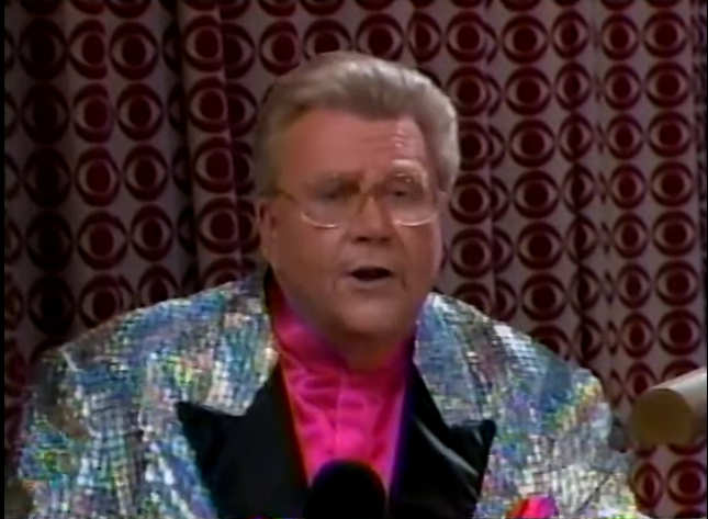 Rod is wearing a silver jacket with black lapels & a fuchsia collarless silk shirt with matching pocket square