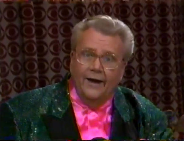 Rod is wearing a dark-green sequined jacket with black lapels & a pink collarless silk shirt