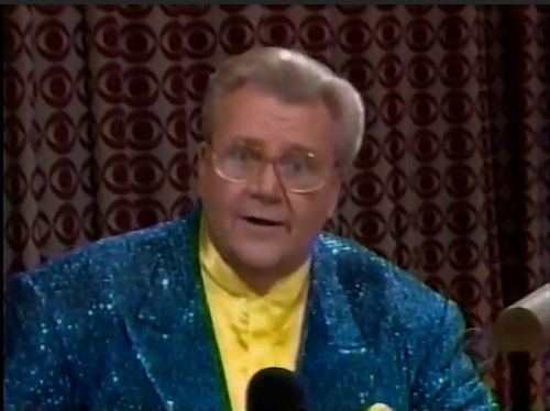 Rod is wearing a blue sequined jacket & yellow collarless silk shirt with matching pocket square