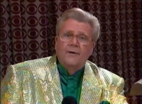Rod is wearing a gold sequined jacket & dark-green collarless silk shirt with matching pocket square