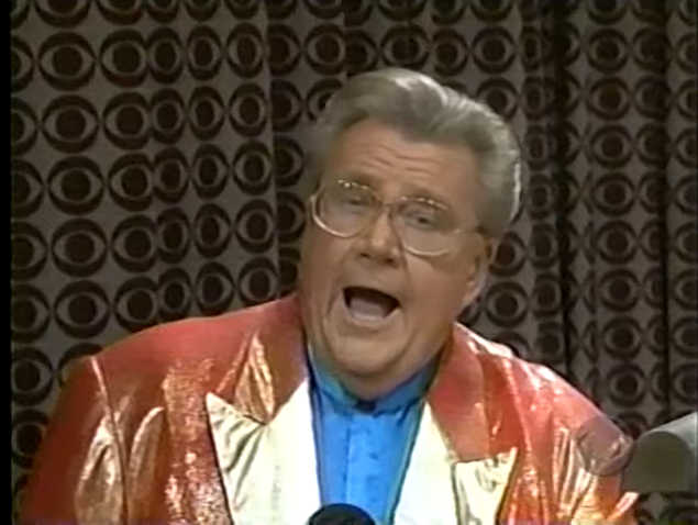 Rod is wearing a shiny salmon-colored jacket with gold lapels & light-blue collarless silk shirt