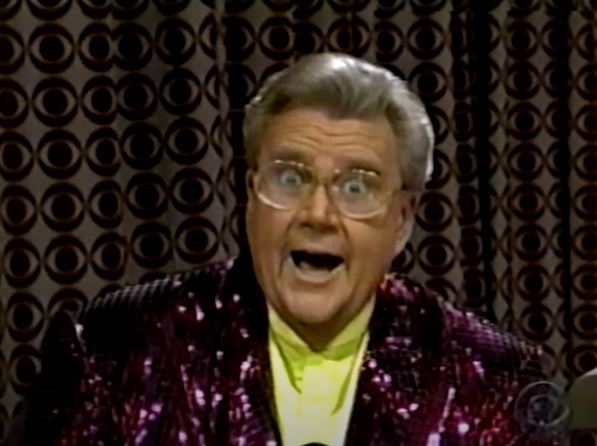 Rod is wearing a dark-red sequined jacket & yellow collarless silk shirt