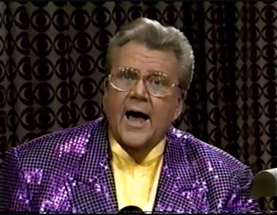Rod is wearing a purple sequined jacket & yellow collarless silk shirt