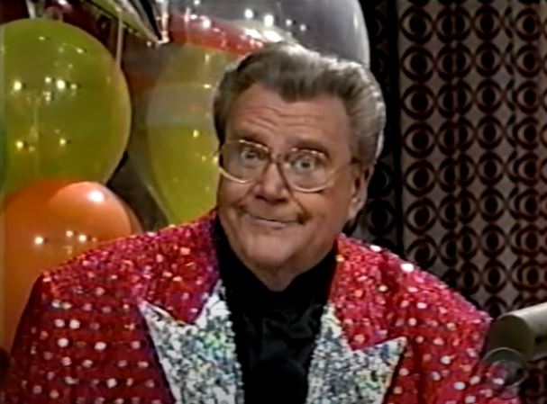 Rod is wearing a red sequined jacket with silver dots and silver lapels & black collarless silk shirt