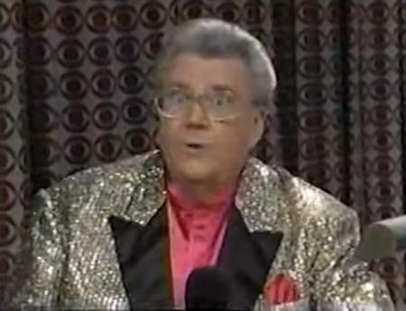 Rod is wearing a gold sequined jacket with black lapels & a salmon collarless silk shirt with matching pocket square