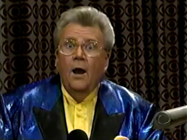 Rod is wearing a shiny blue jacket with black lapels & a yellow collarless silk shirt with matching pocket square