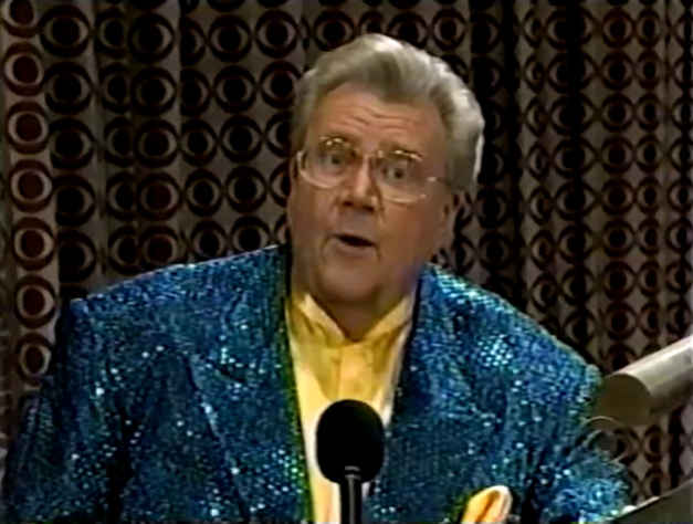 Rod is wearing a teal blue sequined jacket & yellow collarless silk shirt with matching pocket square