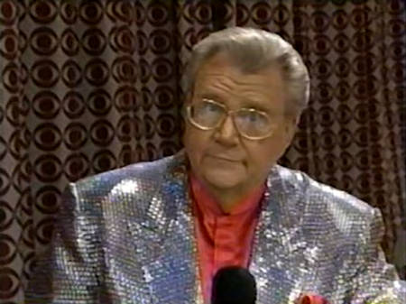 Rod is wearing a silver sequined jacket & salmon collarless silk shirt with matching pocket square