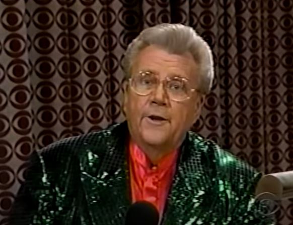 Rod is wearing a dark-green sequined jacket & salmon collarless silk shirt with matching pocket square