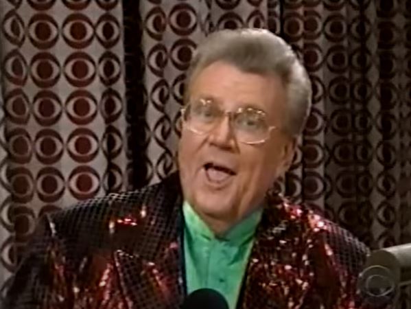 Rod is wearing a dark red sequined jacket & green silk collarless shirt