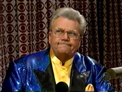 Rod is wearing a shiny blue jacket with black lapels & yellow collarless silk shirt with matching pocket square