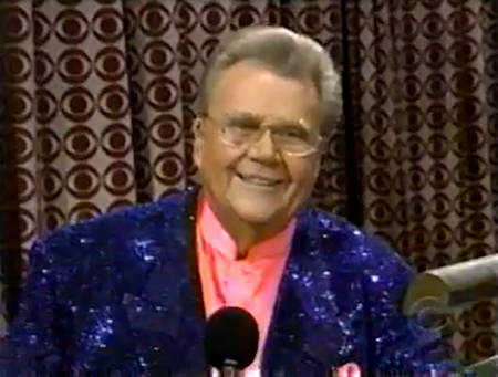 Rod is wearing a dark-blue sequined jacket & pink collarless silk shirt with matching pocket square