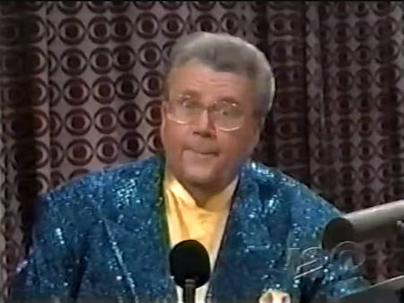 Rod is wearing a teal sequined jacket & yellow collarless silk shirt with matching pocket square