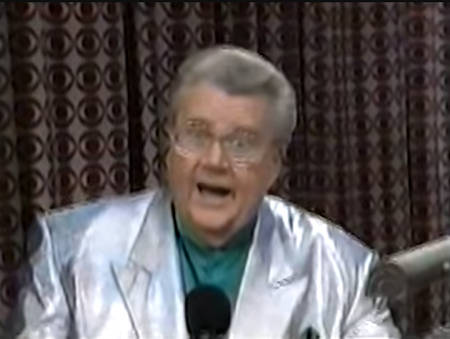 Rod is wearing a shiny silver jacket & teal collarless silk shirt