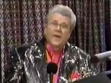 Rod is wearing a black sequined jacket and salmon collarless silk shirt with matching pocket square