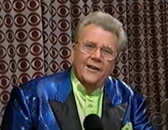 Rod is wearing a shiny dark-blue jacket with black lapels & a lime-green collarless silk shirt with matching pocket square