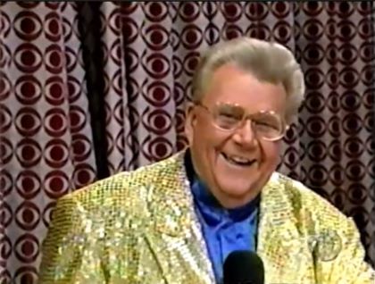 RRod is wearing a gold-sequined jacket & blue collarless silk shirt