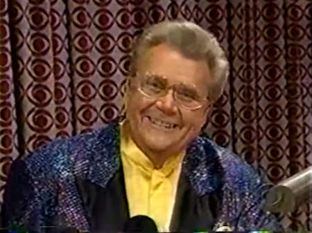 Rod is wearing a blue and purple sequined jacket & yellow collarless silk shirt