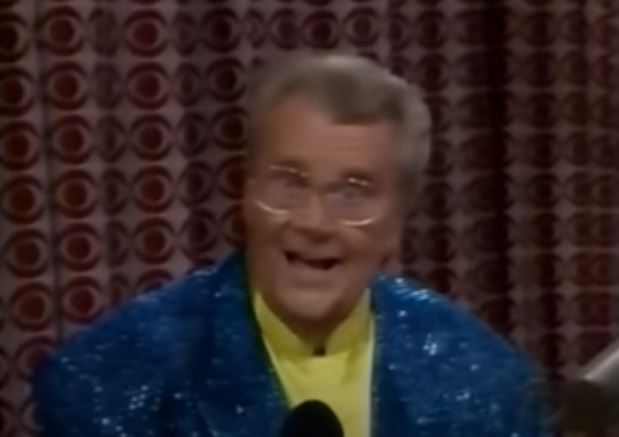 Rod is wearing a blue sequined jacket & yellow silk collarless shirt